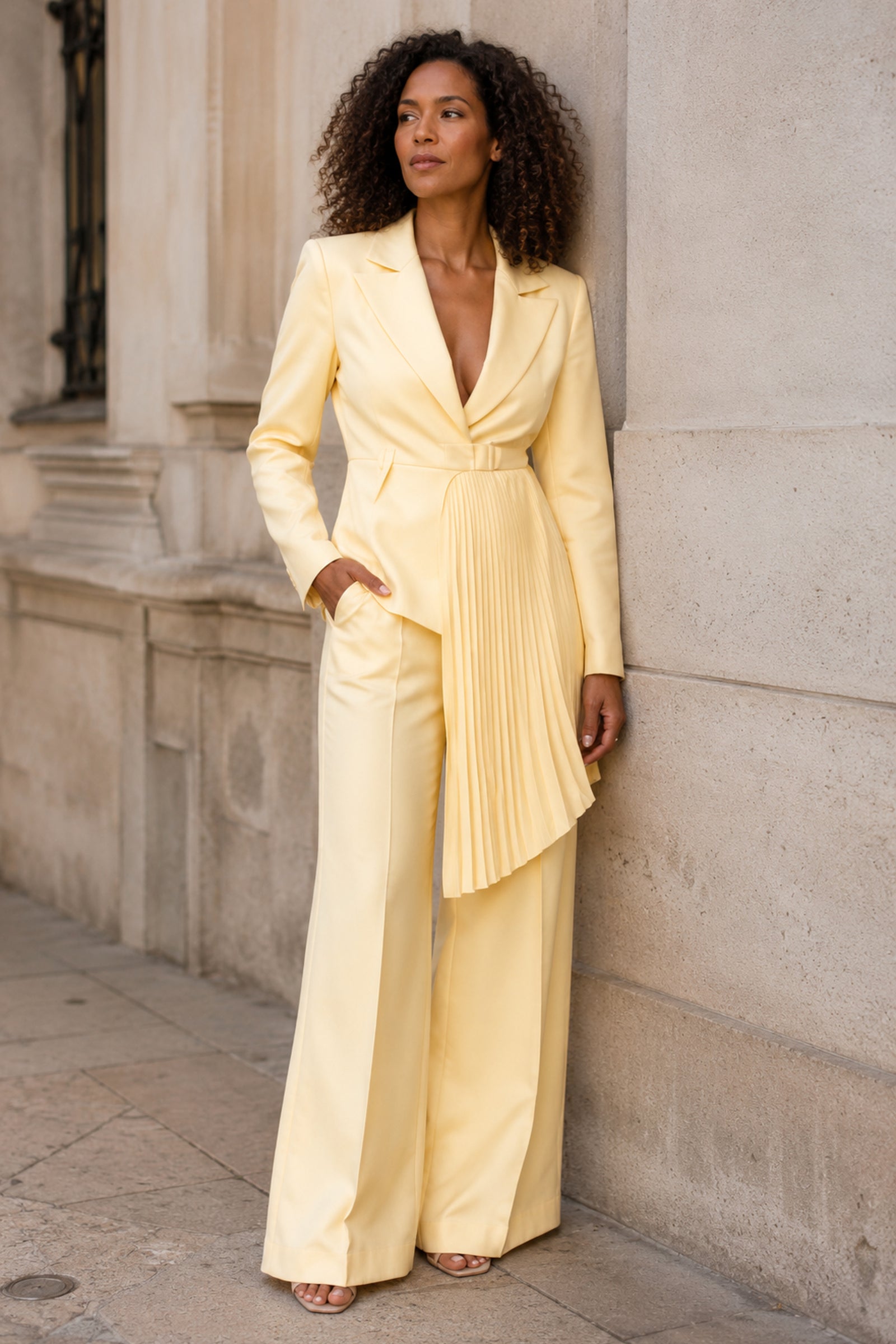 Solevia Pleated Pants Set in a three-quarter pose beside a stone wall