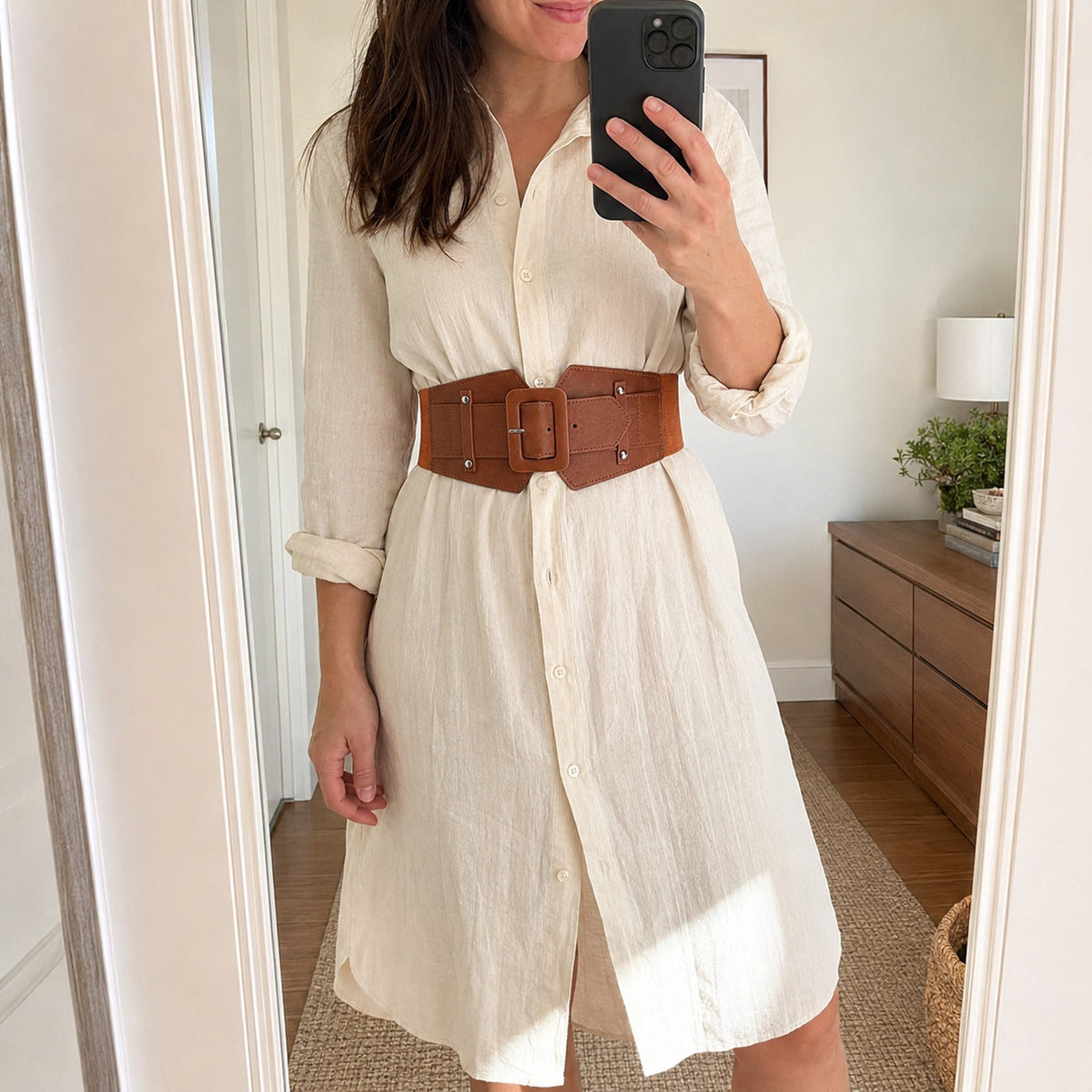 Woman styling the cognac Vale Cinch Belt over an ivory shirt dress in a mirror selfie